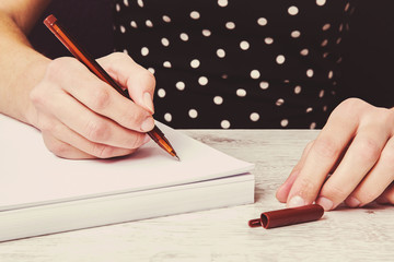 Hands writing something on the white paper. Writing a letter.