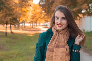 cute pin-up girl in a Brown scarf stands in the Park and smiles