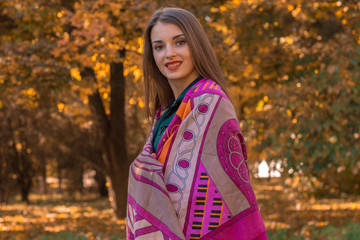 young girl stands in the Park in  large scarf on the shoulders