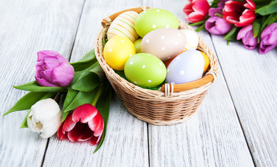 basket with easter eggs and tulips