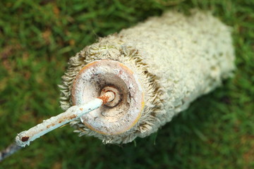 Used and old dirty roller type paint brush put on the grass floor represent the painting equipment material concept related idea.