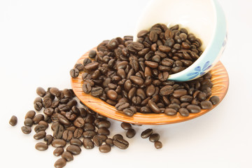 Coffee bean in a White coffee cup and a brown dish on white background.
