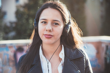 Young beautiful long hair caucasian woman listening music with headphones and smart phone hand hold...