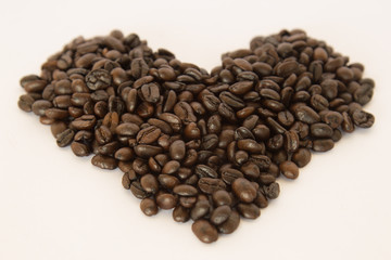 Coffee beans arranged in a heart shape on white background.