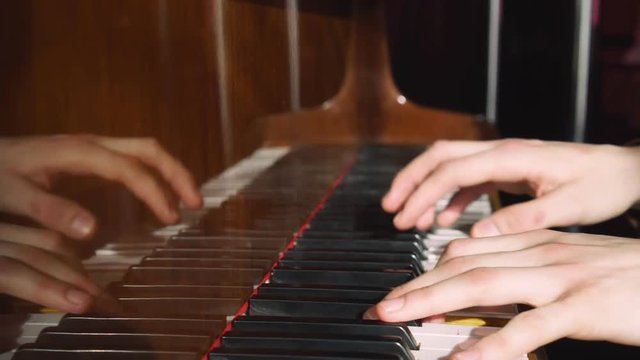 Playing piano. The young man plays a piano. The beautiful pianist plays melodies. Pleasant light from a window indoors. The Pproffesionalny pianist for a piano. Hands it is close to the camera. The