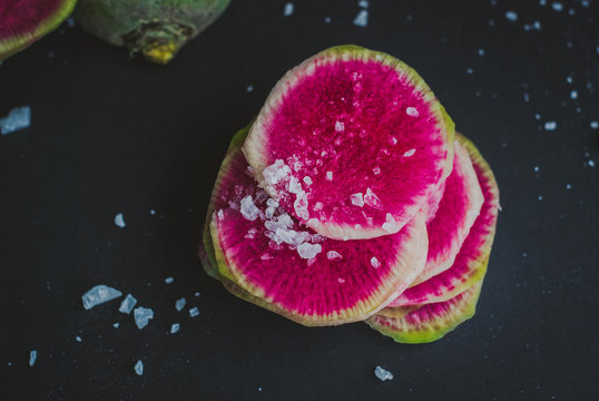 Watermelon Radishes Sliced, Sprinkled with Sea Salt on a black background