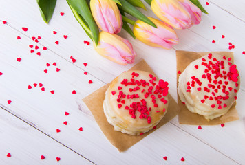 Obraz na płótnie Canvas Honey Cake, Sprinkled Red Hearts, with a Bouquet of Tulips on a White Background.