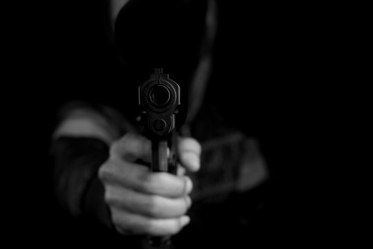 Man holding and shoot gun thief or bandit on dark black background
