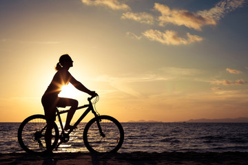 Fototapeta na wymiar happy woman with bicycle standing on the beach