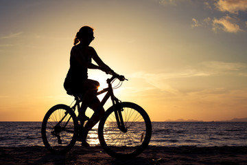 happy woman with bicycle standing on the beach