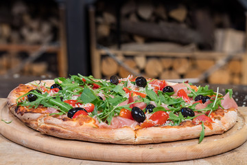 Pizza prosciutto crudo e rucola with cherry tomatoes and olives