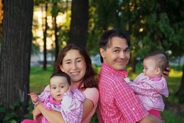  Happy family at the park with father, mother and infant twins baby - sisters