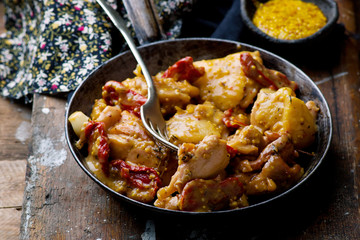 Braised chicken with dried tomatoes in frying pan