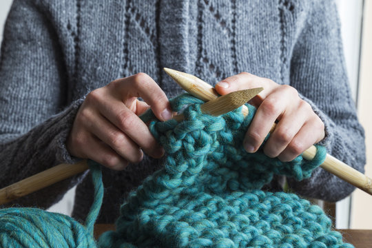 Woman knitting scarf with green wool