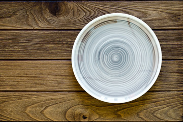 Empty earth tone plate on wooden background. Top view with copy space