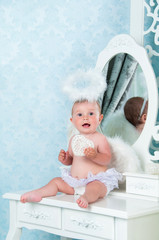 Little angel smiling and sitting on the dressing table