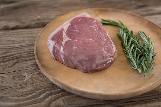Sirloin chop and rosemary on wooden tray 
