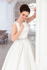 Fototapeta premium close-up portrait of beautiful brunette bride with elegant hairstyle and makeup wearing long luxury wedding dress