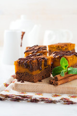 Chocolate brownie with a pumpkin on a light background. Selective focus.