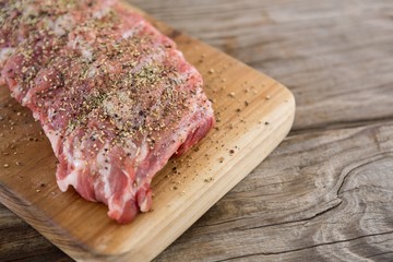 Raw beef ribs on wooden tray against wooden background