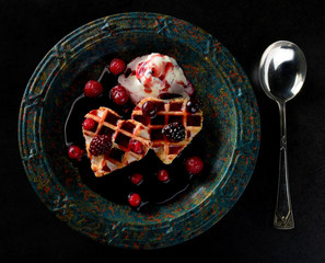 Romantic dessert with hearts of waffels, ice cream and fruit sauce. Dark and gothic.