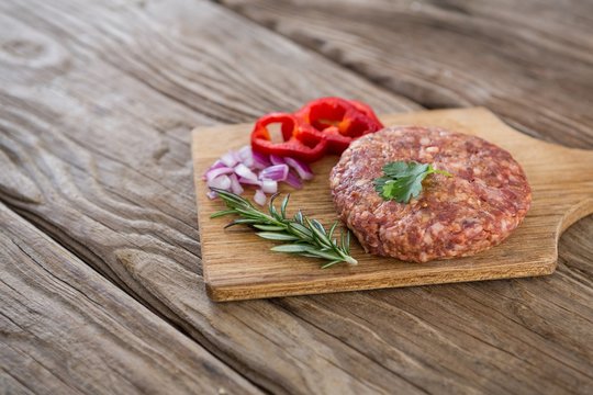 Beef patty and ingredients on wooden tray 