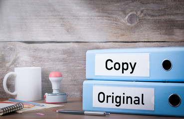 Original and Copy. Two binders on desk in the office. Business background.