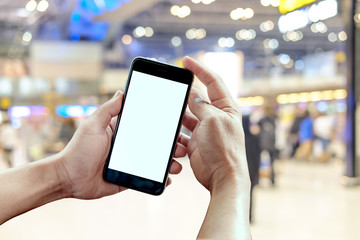man holding and using smartphone in airport terminal.