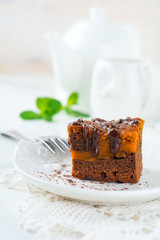 Chocolate brownie with a pumpkin on a light background. Selective focus.