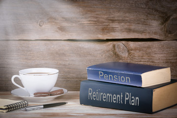 Retirement Plan and Pension. Stack of books on wooden desk.