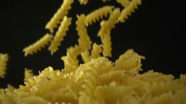 Italian fusilli falling. Spirelli pasta on dark background. Slow motion shot