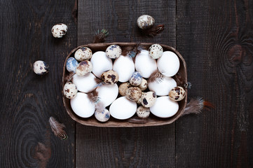Various fresh raw eggs and feathers on the wooden table