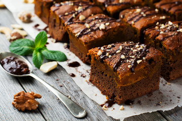 Chocolate brownie with a pumpkin on a old wooden background. Homemade Cake square pieces. Selective focus.