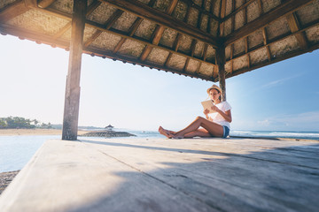 Relaxed and cheerful. Work and vacation. Outdoor portrait of happy young woman using tablet computer on terrace near the sea.