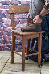 Close Up of One Person who wears boots for trekking and Mountain, with close Tools and Accessories as a compass, backpack, drinking bottle and  ax Rock
