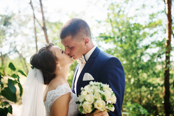 Loving young wedding couple in love at sunny forest.