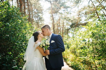 Loving young wedding couple in love at sunny forest.