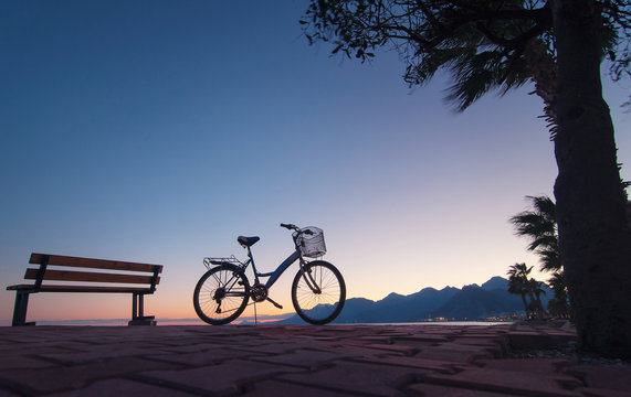Silhouette of bicycle near the bench.