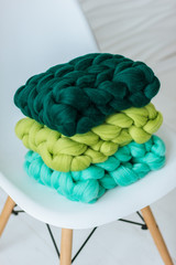Colorful knitted merino wool scarves on white chair