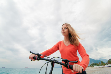 woman walking near the sea with bicycle
