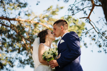 Loving young wedding couple in love at sunny forest.