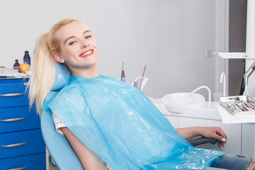 Girl in the dentist office sits in a chair with a smile