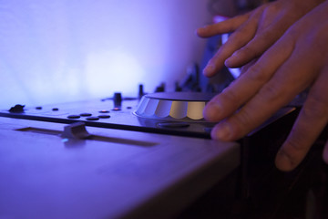 close up of a music dj mixing tracks on his electronic console