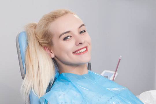 Girl in the dentist office sits in a chair with a smile