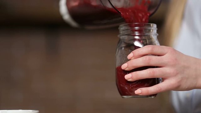 Closeup pouring beet smoothie from blender to jar