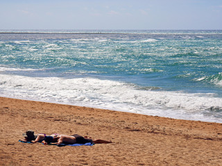 Couple sun tanning on a windy beach