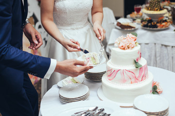 bride and groom cut rustic wedding cake on wedding banquet with pink rose and other flowers and...