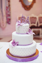 Sweet multilevel wedding cake on wedding banquet decorated with  violet.flowers,ribbons and letters 