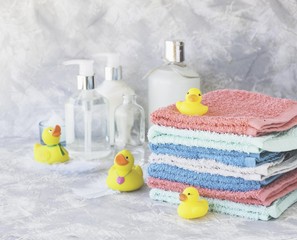stack of towels with yellow rubber bath ducks on white marble background, space for text, selective focus
