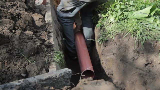 Plumber sewer pipe/Plumber working outdoors paving sewer pipes